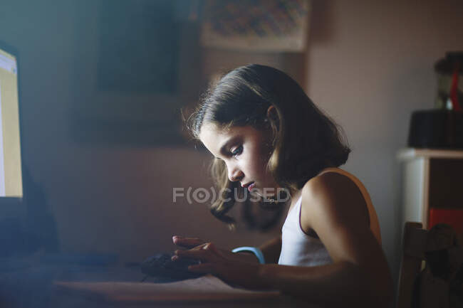Girl using computer in dimly-lit room — Stock Photo