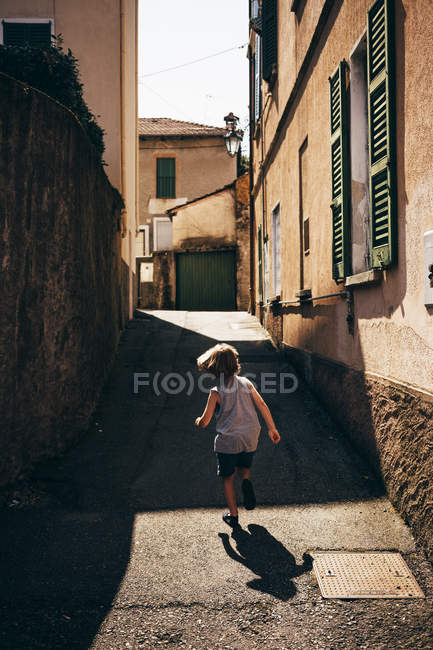 Rear view of boy running up narrow street, Luino, Lombardy, Italy — Stock Photo