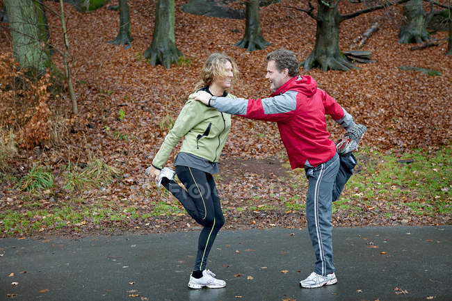 Mature couple leaning together to perform warming up exercises — Stock Photo