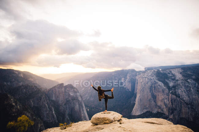 Mujer joven de pie en postura de yoga, en la cima de la montaña con vistas al Parque Nacional Yosemite, California, EE.UU. - foto de stock
