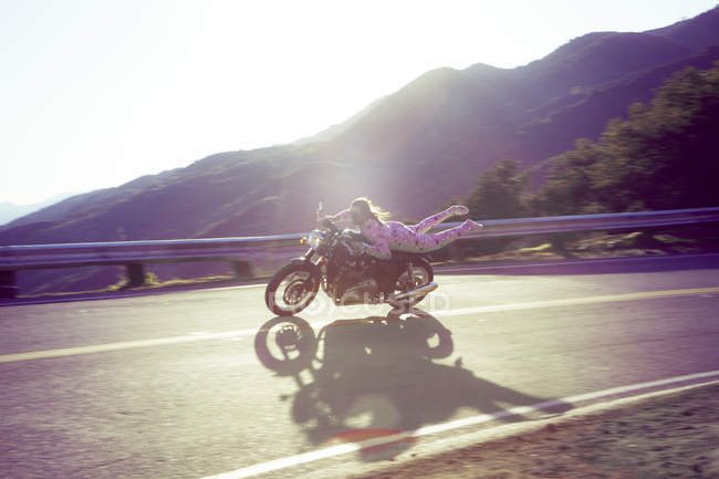 Man wearing pink onesie, riding motorcycle, Malibu Canyon, California, USA — Stock Photo