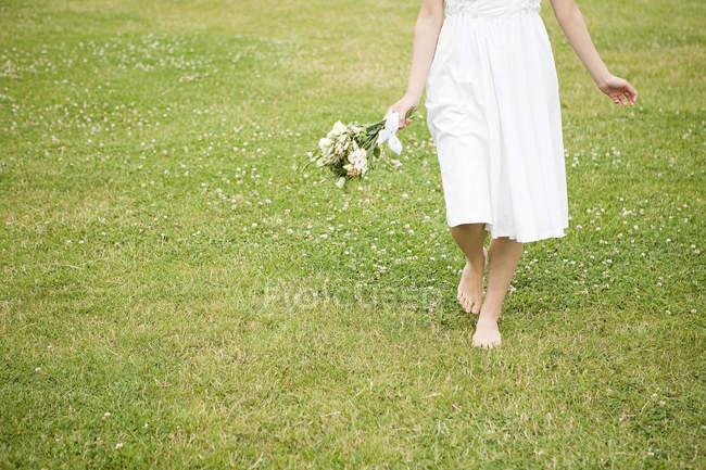 Обрезанное изображение невесты, идущей по траве — стоковое фото