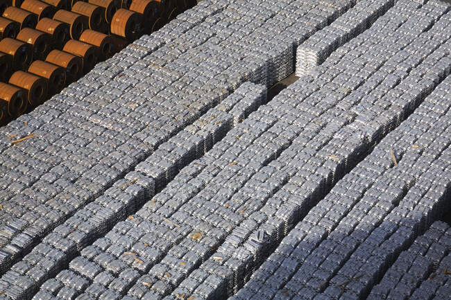 Высокий угол обзора алюминиевых слитков и рулонной стали, ожидающих отгрузки в порту — стоковое фото