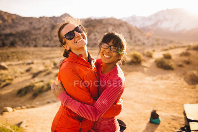 Amici che abbracciano e guardano la macchina fotografica, Buttermilk Boulders, Bishop, California, USA — Foto stock