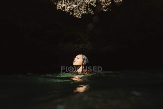 Donna in grotta piena d'acqua con gli occhi chiusi, Oahu, Hawaii, USA — Foto stock