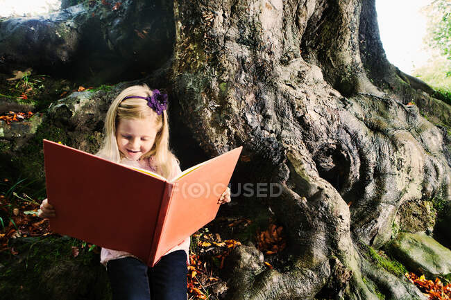 Jeune fille lisant un livre dans une forêt — Photo de stock