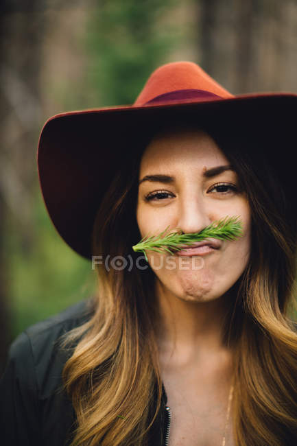 Portrait of woman with foliage moustache pulling face, Rocky Mountain National Park, Colorado, USA — Stock Photo