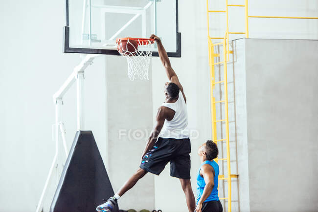 Male basketball player throwing ball into hoop on basketball court — Stock Photo