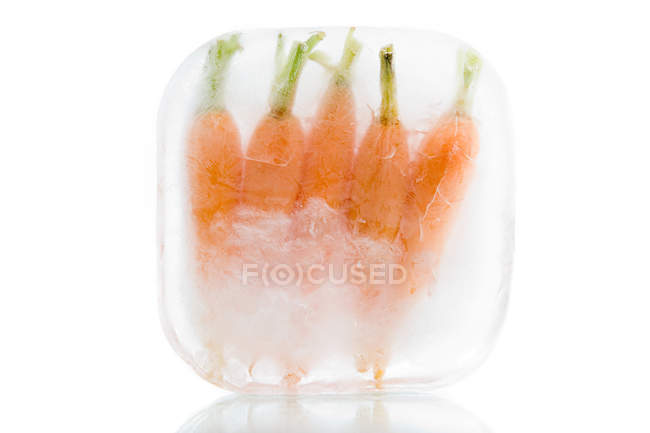 Frozen carrots in ice block — Stock Photo