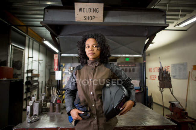 Retrato de joven hembra metalúrgica en taller de soldadura - foto de stock