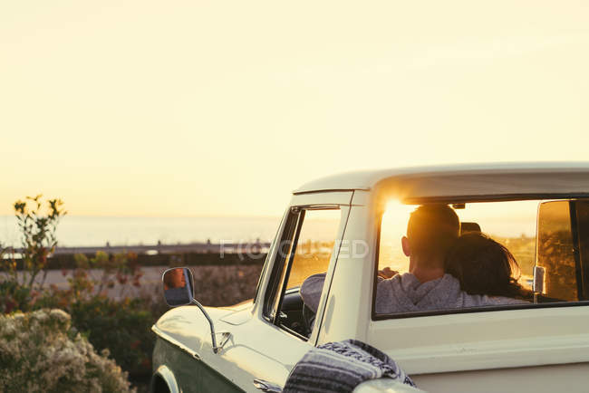 Rückansicht eines Paares im Pickup-Truck, das den Sonnenuntergang am Newport Beach, Kalifornien, USA beobachtet — Stockfoto