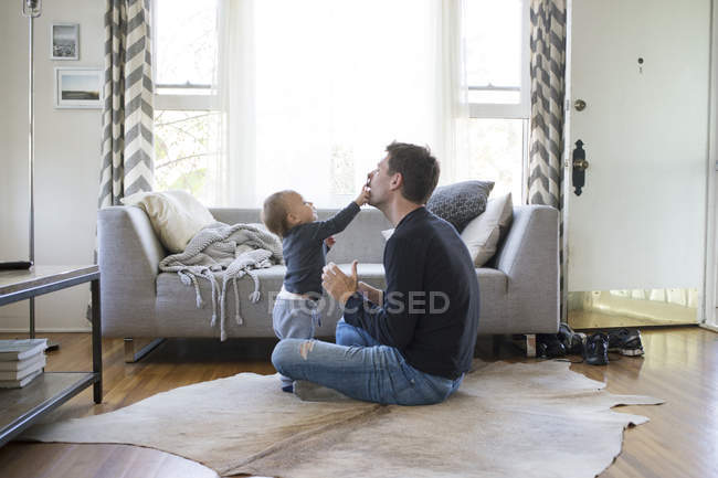 Батько і молодий син вдома, граючи разом — стокове фото