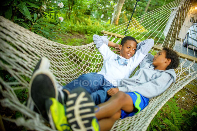 Niños acostados en una hamaca en la naturaleza - foto de stock