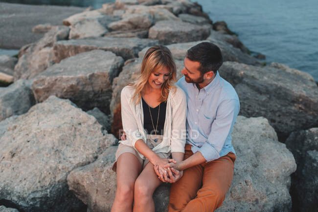 Romantic couple holding hands on boulder wall, Lake Ontario, Toronto, Canada — Stock Photo
