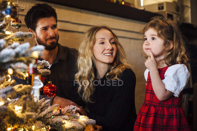 Femmina bambino con i genitori guardando l'albero di Natale — Foto stock