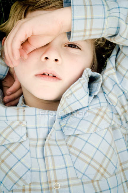 Overhead portrait of boy covering eye with hand — Stock Photo
