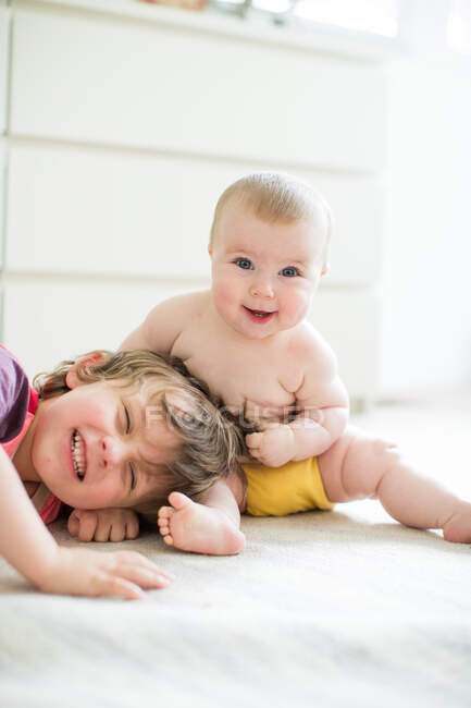 Jovem brincando com a irmã bebê, dentro de casa — Fotografia de Stock
