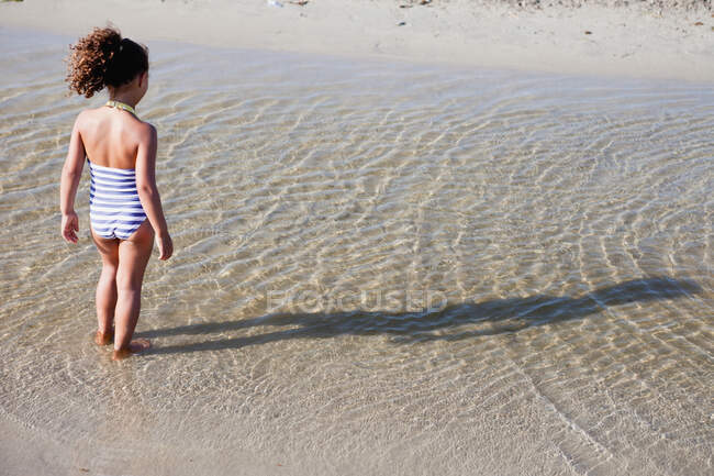 Junges Mädchen spielt im Wasser am Strand — Stockfoto