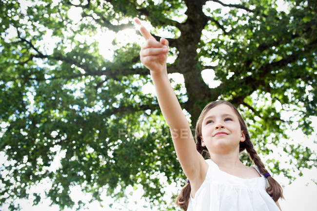 Girl pointing under tree — Stock Photo