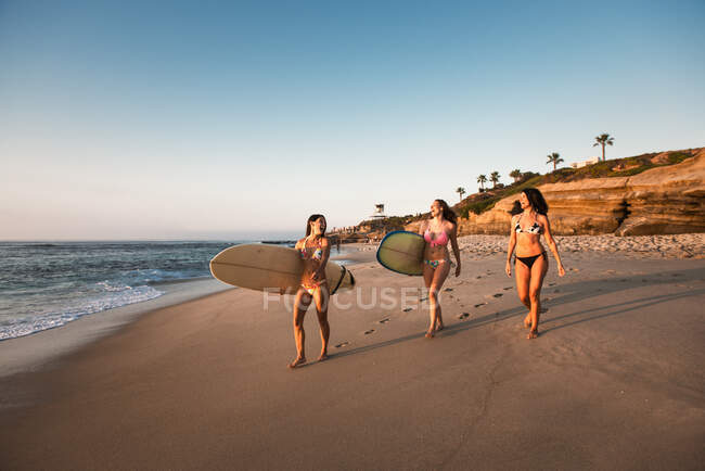 Surfers carrying surf boards, walking along beach — Stock Photo