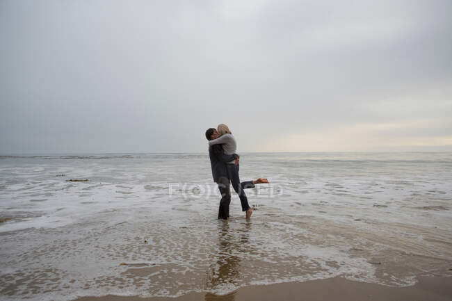 Зрелая пара обнимается на пляже — стоковое фото