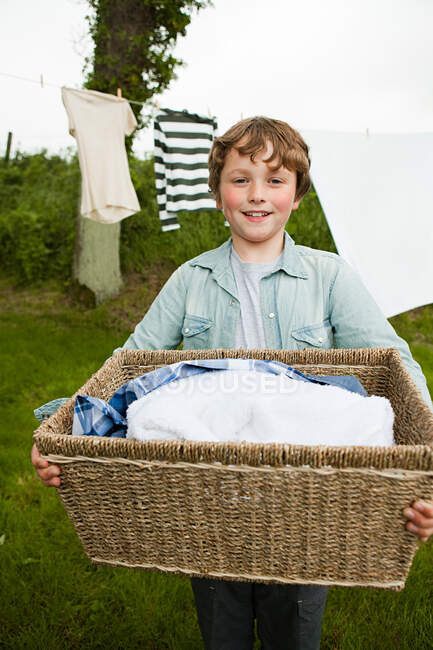 Niño llevando cesta de lavado - foto de stock