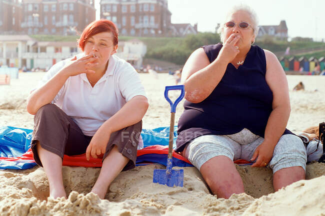 Дві жінки курять на пляжі — стокове фото