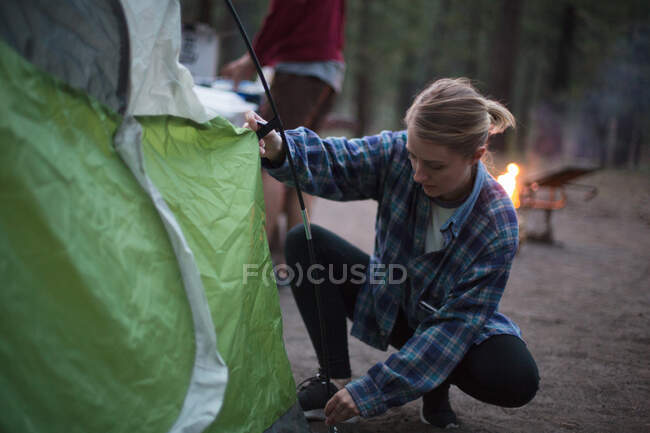 Молодая женщина, пытающаяся приготовить палатку в сумерках, озеро Маммот, Калифорния, США — стоковое фото