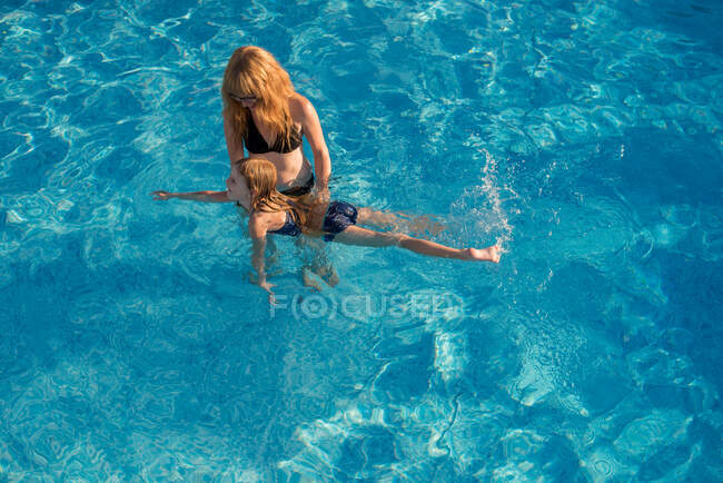 Madre e figlia in piscina, madre insegnando figlia a nuotare — Foto stock