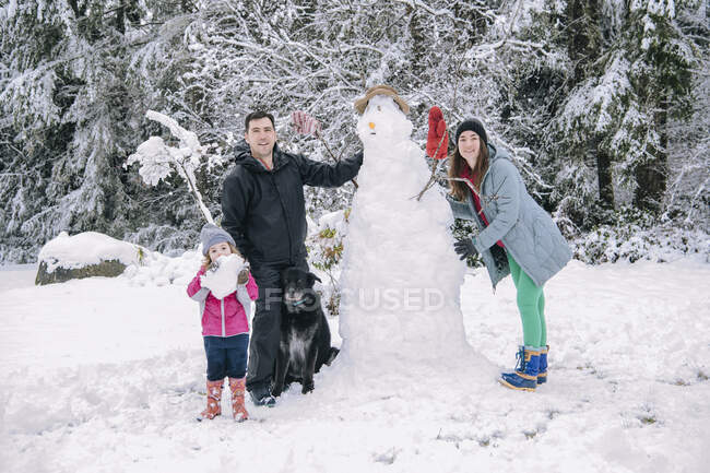 Portrait de jeune famille, bonhomme de neige bâtisseur — Photo de stock