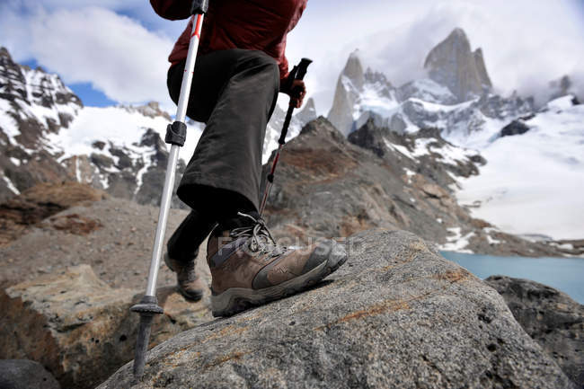 Woman takes a step with trekking poles at the Monte Fitz Roy Lookout in Los Glaciares National Park, El Chalten, Argentina — Stock Photo