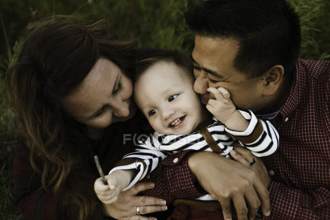 Madre y padre abrazando al niño sonriente - foto de stock