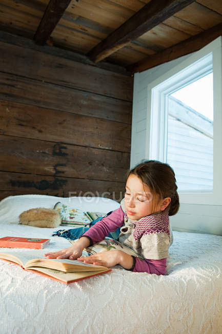 Молода дівчина лежить на ліжку читання книга — стокове фото