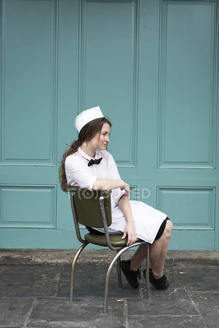 Женщина в форме официантки, сидит в кресле — стоковое фото