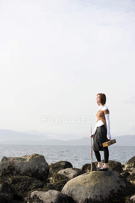 Молода жінка на каменях біля моря — стокове фото