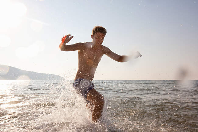 Giovane uomo schizzi in mare — Foto stock