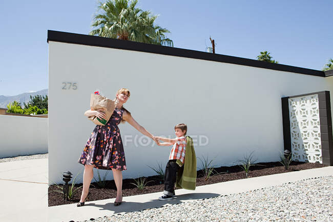 Mother holding shopping bag and pulling son's arm — Stock Photo
