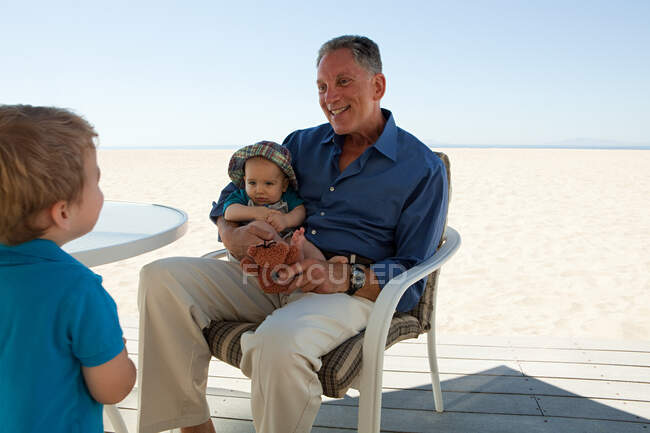 Abuelo sentado con dos nietos - foto de stock