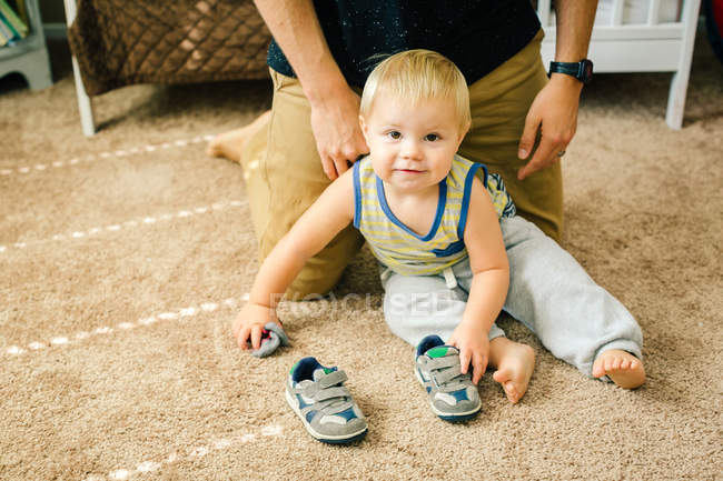 Батько допомагає молодому синові одягнути взуття — стокове фото