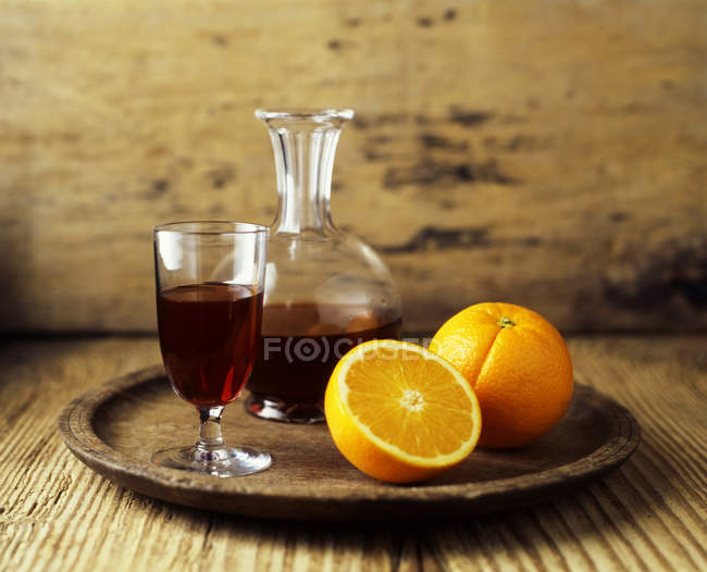 Rotweinkaraffe, Glas und frische Orangenfruchthälften auf Holztablett — Stockfoto