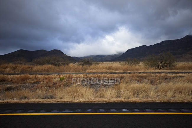 Bahngleise neben trockenem Feld und Gebirge — Stockfoto