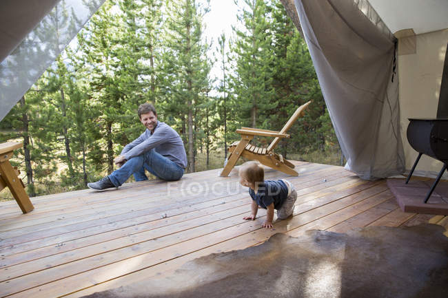 Padre e hijo pequeño en veranda de cabaña - foto de stock