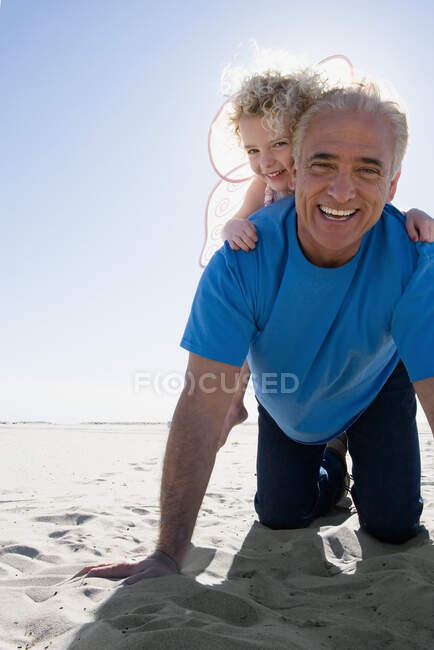 Дедушка играет с внучкой на пляже — стоковое фото