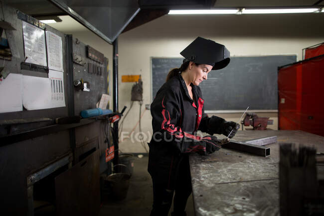 Женщина-кузнец изучает металлический стержень на стенде цеха — стоковое фото