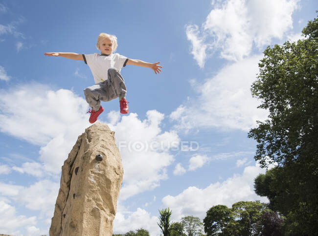 Boy jumping from rock — Stock Photo