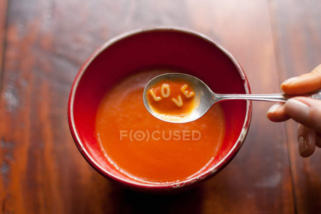 Mão segurando colher cheia de sopa com letras de amor — Fotografia de Stock