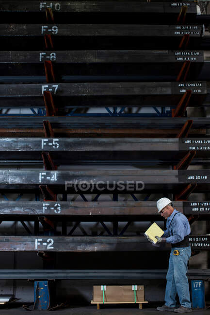 Працівник з папкою на металевому заводі. — стокове фото