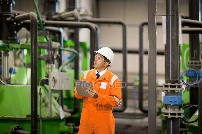 Ingeniero inspeccionando maquinaria en fábrica - foto de stock