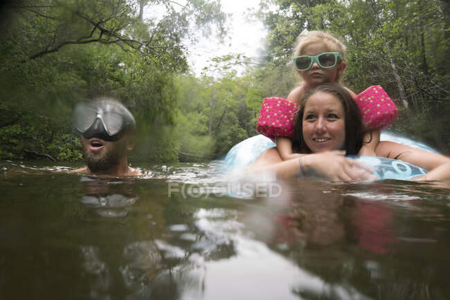 Madre, padre e hija con anillo inflable en el lago, Niceville, Florida, Estados Unidos - foto de stock