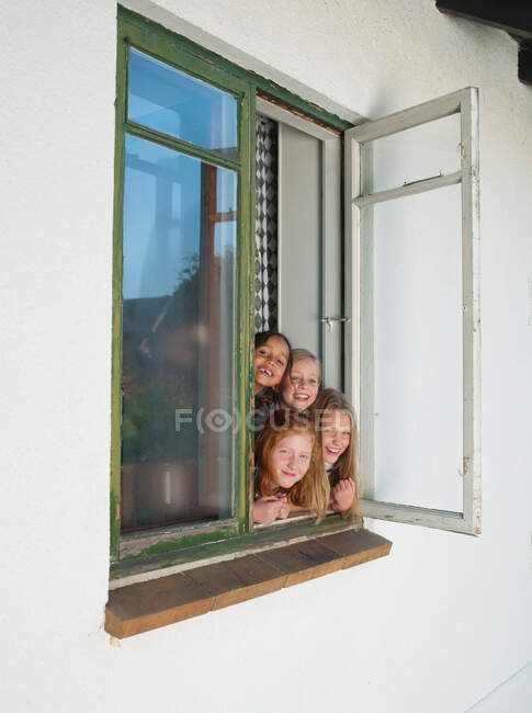 Girls looking through open window, portrait — Stock Photo